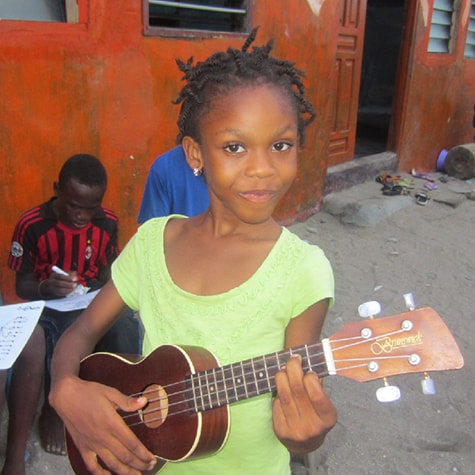 Child learning guitar music in Ghana